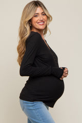 woman wearing a black long sleeve maternity top and showing her baby bump