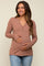 woman wearing a dusty rose long sleeve maternity top with buttons and holding her baby bump