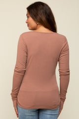 woman wearing a mauve long sleeve maternity top, viewing from the back, paired with light blue jeans