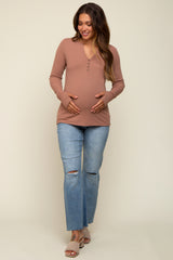 woman wearing a dusty rose long sleeve maternity top with buttons and holding her baby bump with ripped jeans