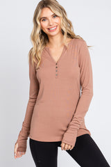 woman wearing a soft brown long sleeve henley top with a v-neck and button details, paired with black leggings