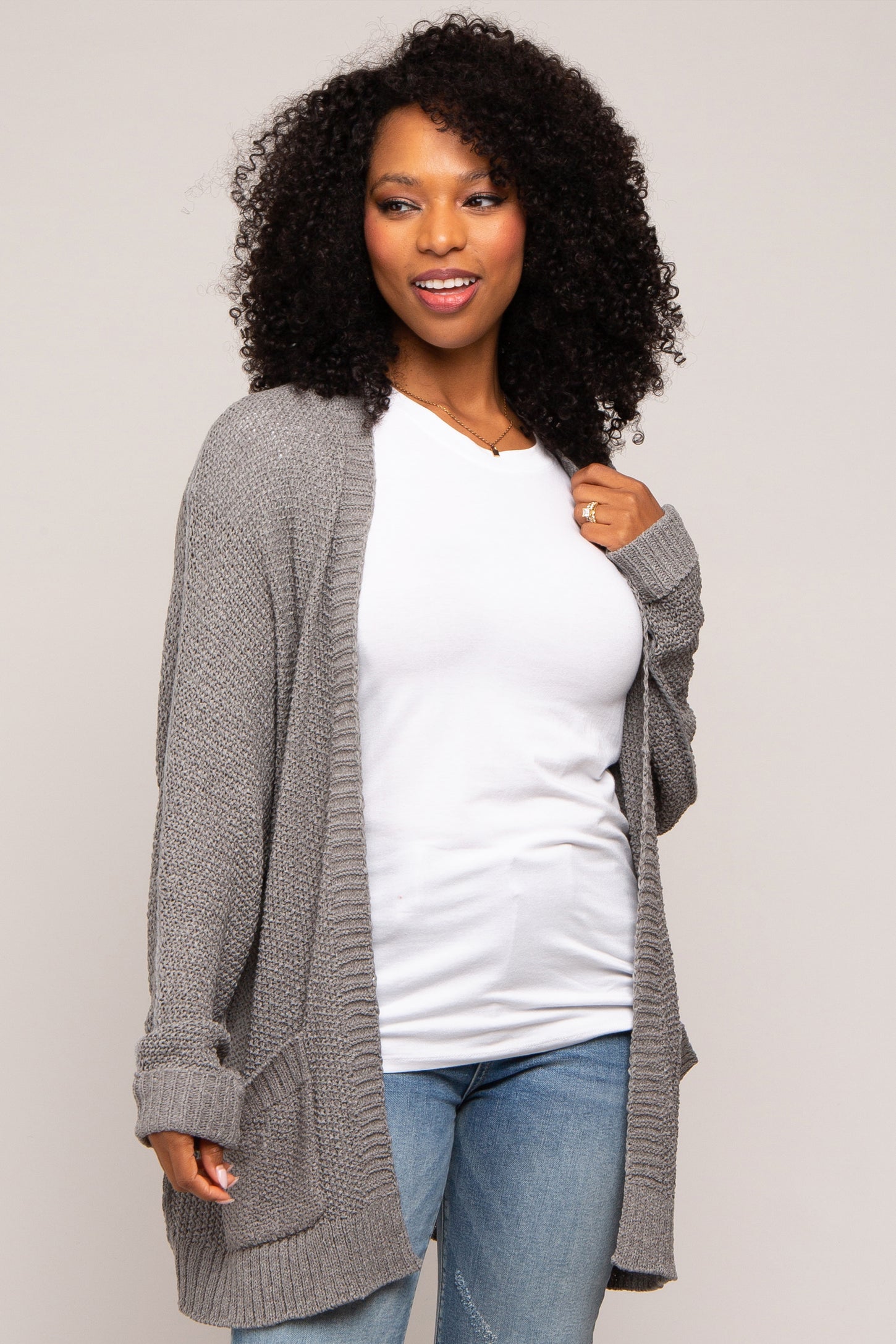 woman wearing a gray oversized cardigan over a white t-shirt and blue jeans