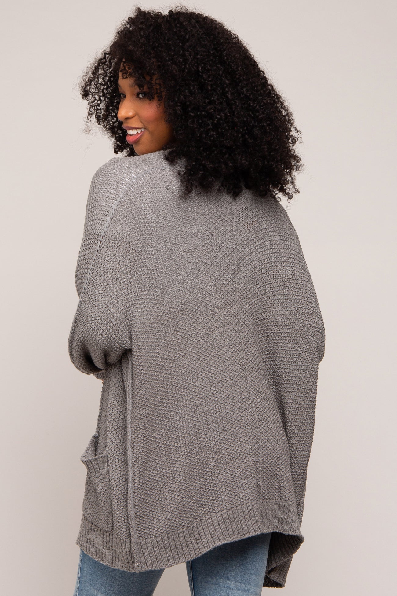 woman wearing a gray oversized knit cardigan with pockets, shown from the back
