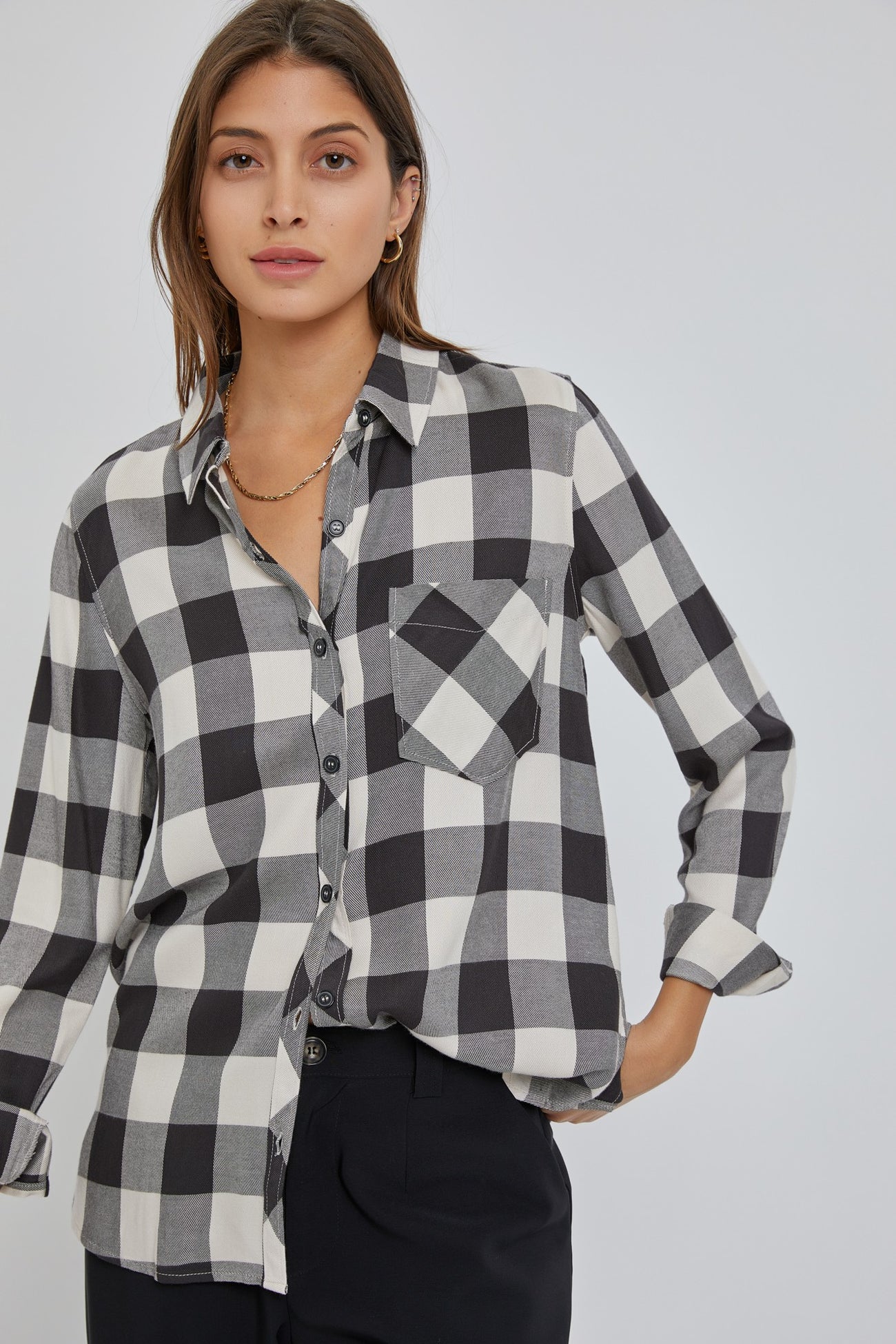 woman wearing a black and white buffalo plaid button-down shirt with gold jewelry