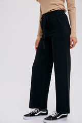 person wearing black wide leg knit trousers with drawstring waist and tan long sleeve top