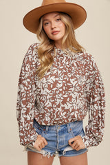 woman wearing brown floral print long sleeve blouse with denim shorts and a wide brim felt hat