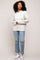 woman wearing a light grey cable knit hoodie with oversized sleeves and ripped blue jeans