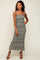 woman wearing a black and green floral maxi dress with spaghetti straps and tiered ruffles, posing confidently