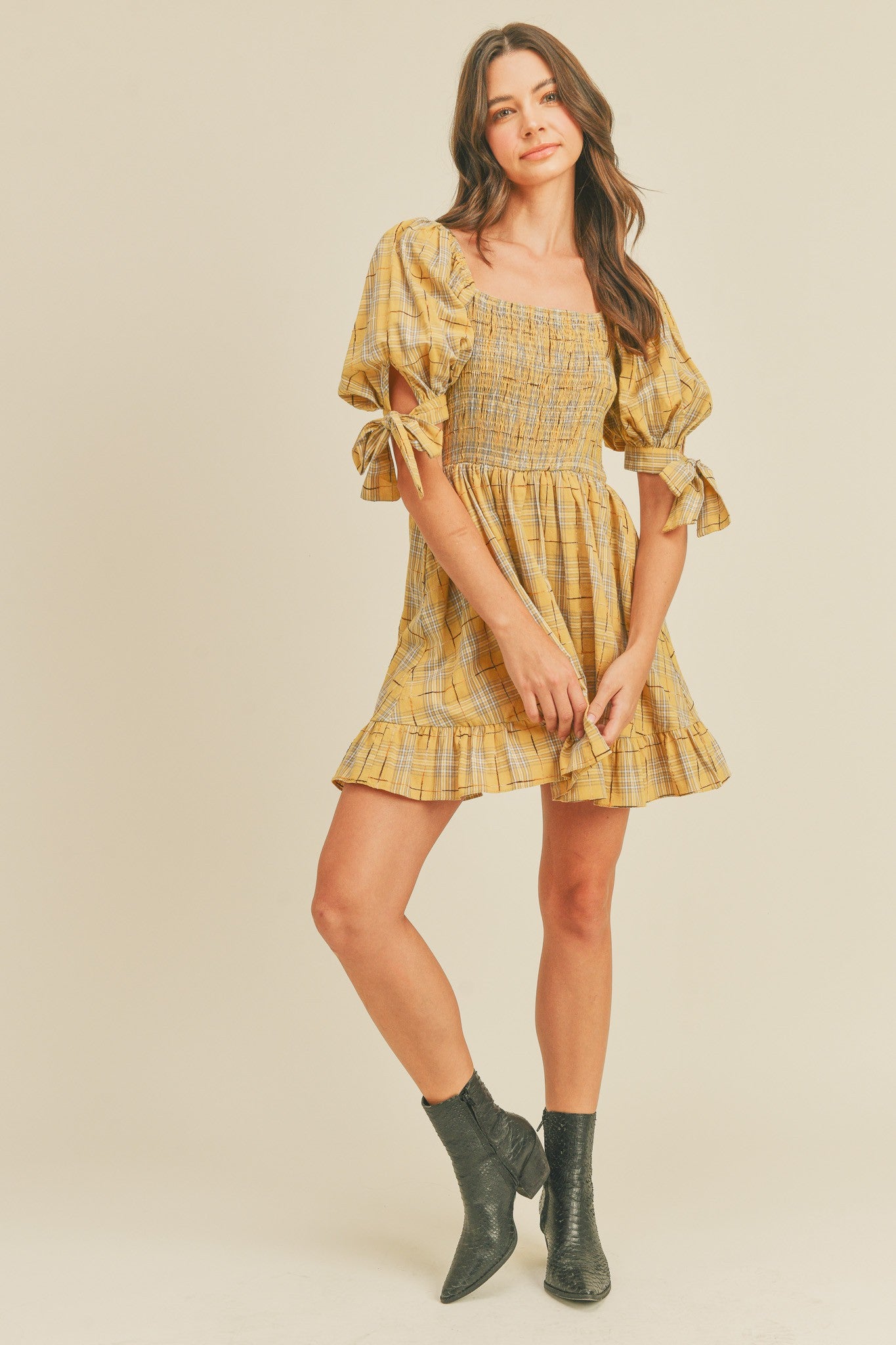 woman wearing a yellow plaid puff sleeve mini dress with a smocked bodice and ruffled hem