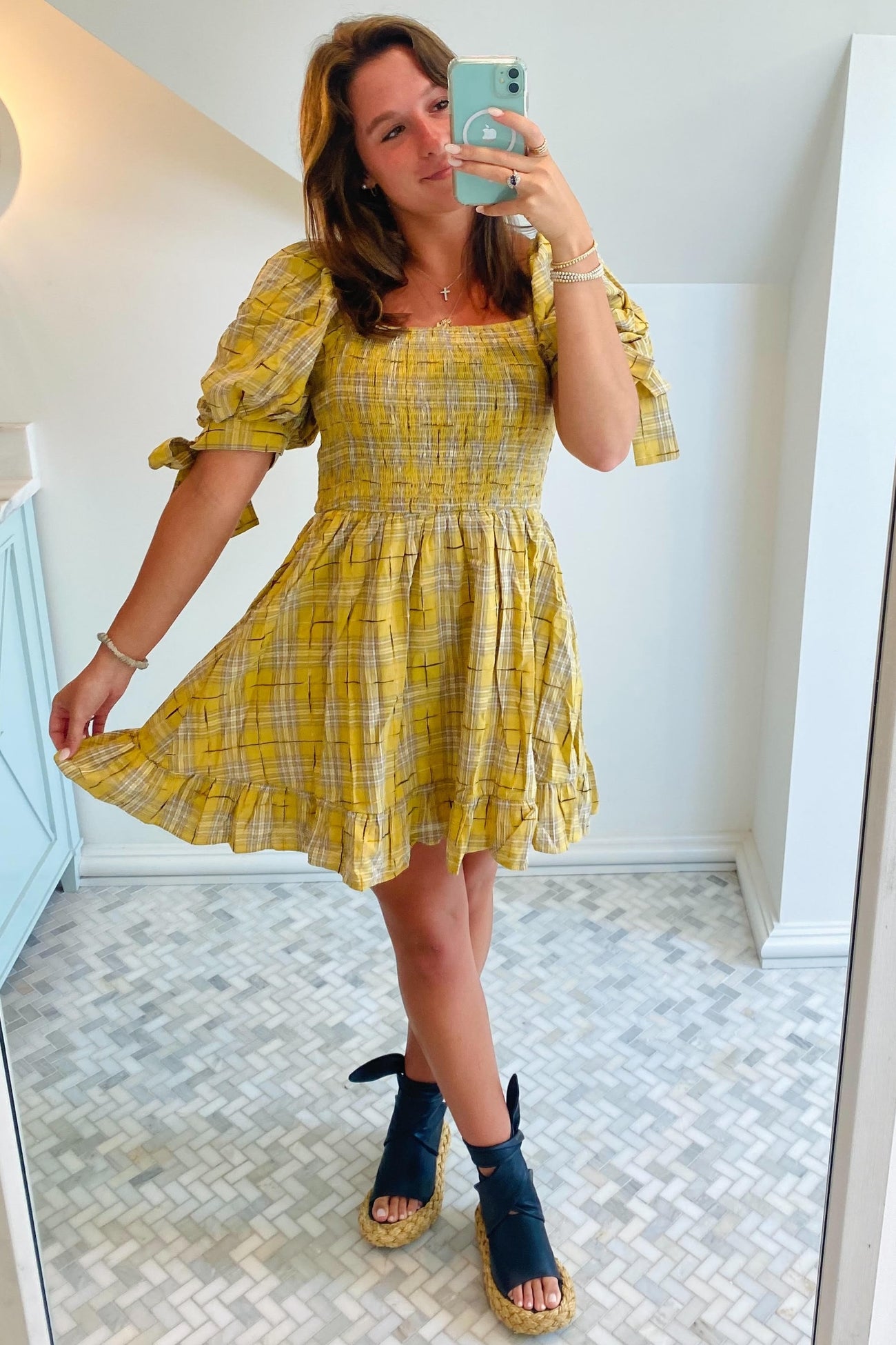 woman wearing a yellow plaid short sleeve dress with a smocked bodice and ruffled hem, standing in front of a mirror