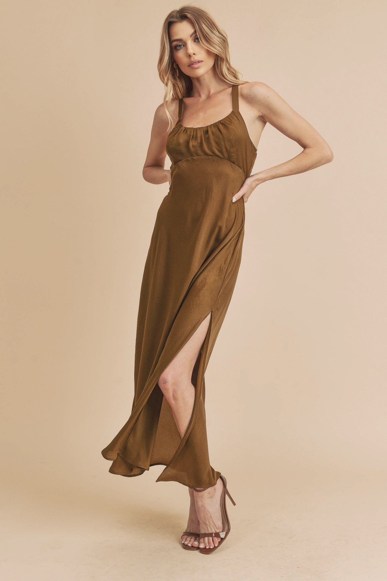 woman wearing a brown sleeveless maxi dress with a side slit and a fitted bodice