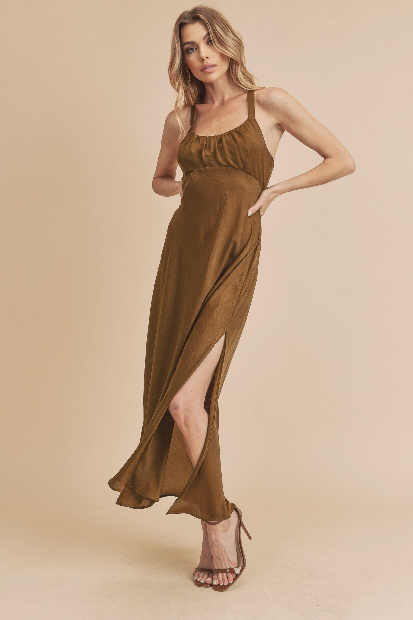 woman wearing a brown sleeveless maxi dress with a side slit and a fitted bodice