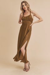 woman wearing a brown sleeveless maxi dress with a side slit and a fitted bodice