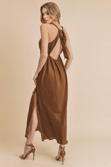 woman wearing a brown satin backless maxi dress with a side slit and high heels