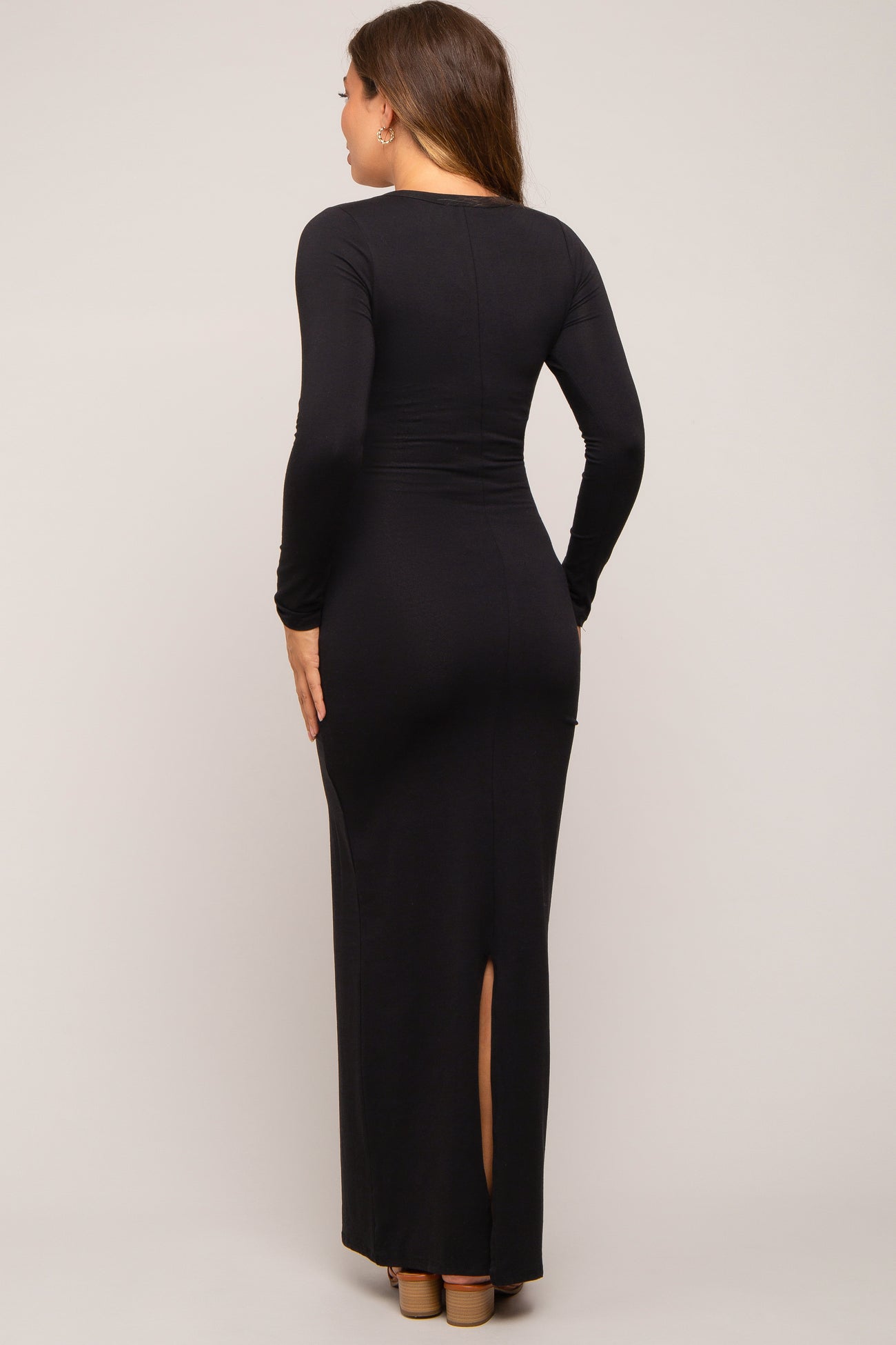 woman wearing a black long sleeve maternity dress with a back slit and a form-fitting silhouette