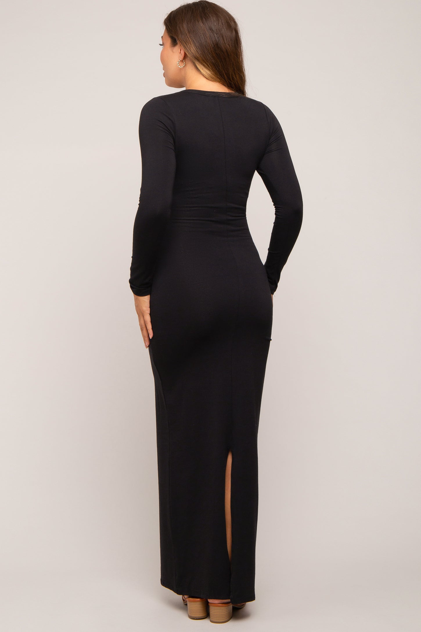 woman wearing a black long sleeve maternity dress with a back slit and a form-fitting silhouette