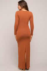 woman wearing a rust long sleeve maternity maxi dress with a back slit