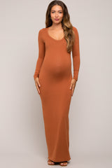 woman wearing a rust long sleeve maternity maxi dress, showing her baby bump