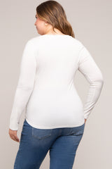 woman wearing a white long sleeve maternity top, viewed from the back with blue jeans
