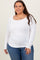 woman wearing a white long sleeve scoop neck top paired with blue jeans