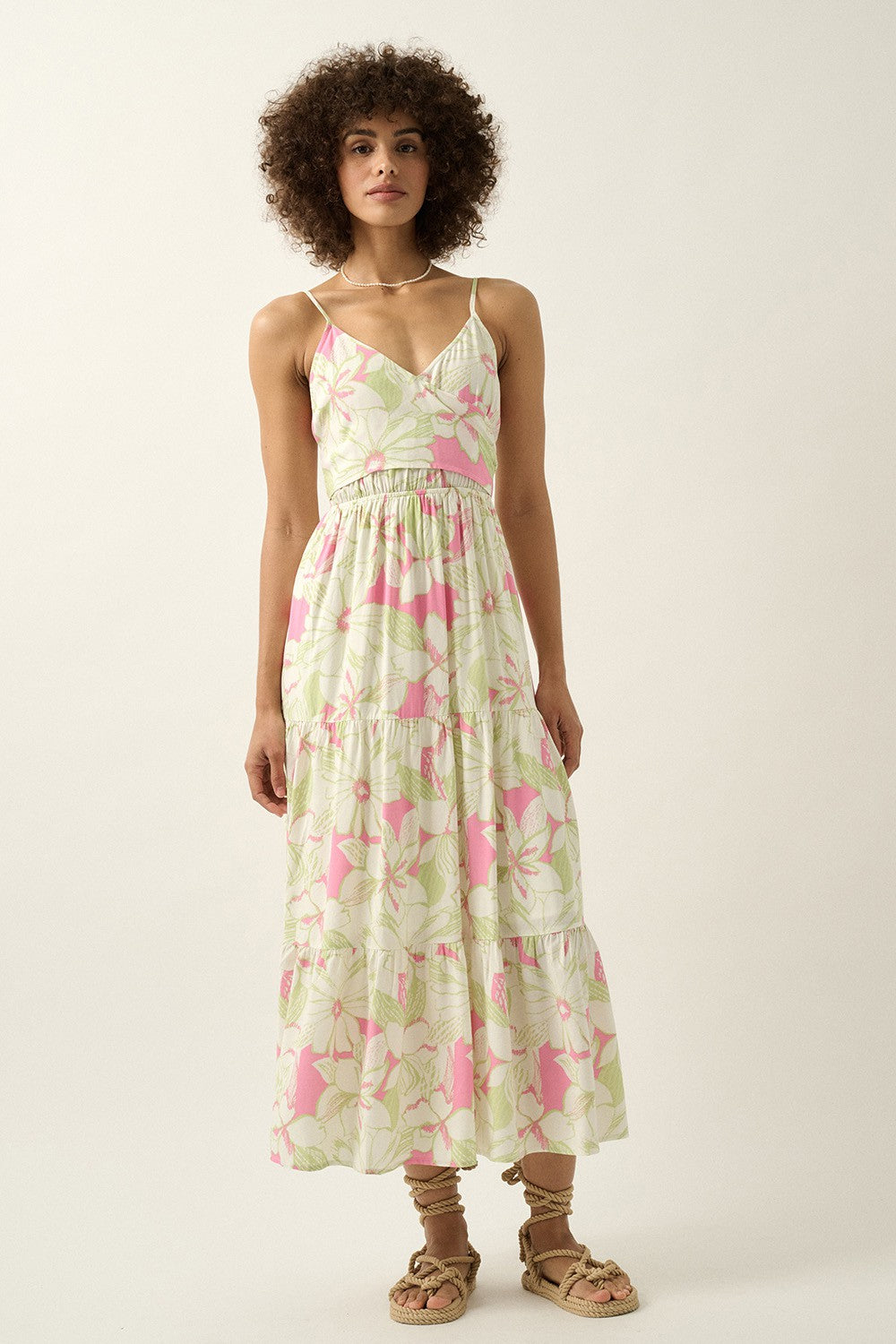 woman wearing a floral maxi dress with spaghetti straps, featuring a tiered hem and a fitted waist
