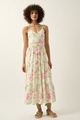 woman wearing a floral maxi dress with spaghetti straps, featuring a tiered hem and a fitted waist