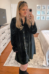 woman wearing a black velvet long sleeve button-up dress, posing with a headband and holding a phone