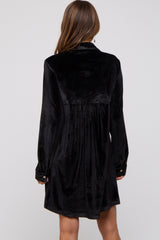 woman wearing a black velvet long sleeve dress with a pleated back and buttoned cuffs, shown from the back