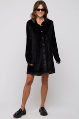 woman wearing a black velvet button-up dress with long sleeves and a relaxed fit, paired with chunky black shoes and sunglasses