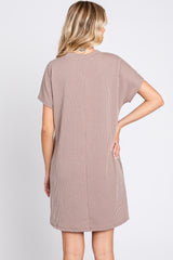 woman wearing a brown striped short sleeve dress, showing the back view and knee-length style