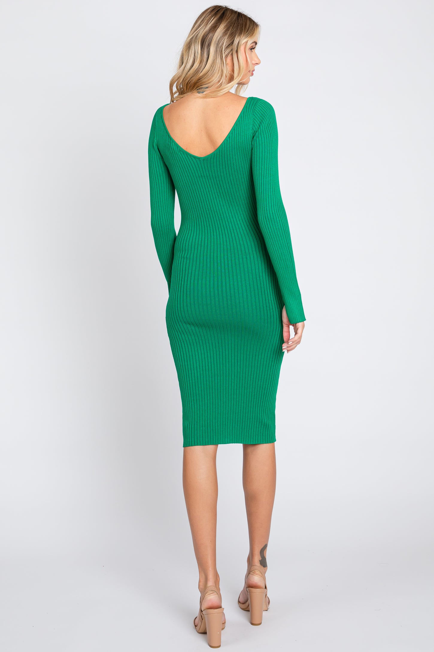 woman wearing a fitted green ribbed midi dress with a deep v-back and long sleeves