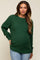 woman wearing a dark green maternity sweater with a textured knit and a visible baby bump