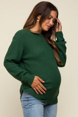 woman wearing a green maternity sweater and holding her baby bump