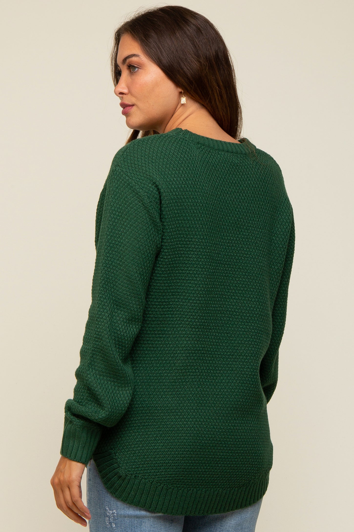 woman wearing a dark green maternity sweater with textured knit and a relaxed fit, showing a baby bump