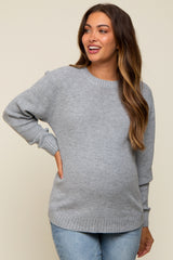 woman wearing a light gray maternity sweater with a textured knit and relaxed fit, showing her baby bump