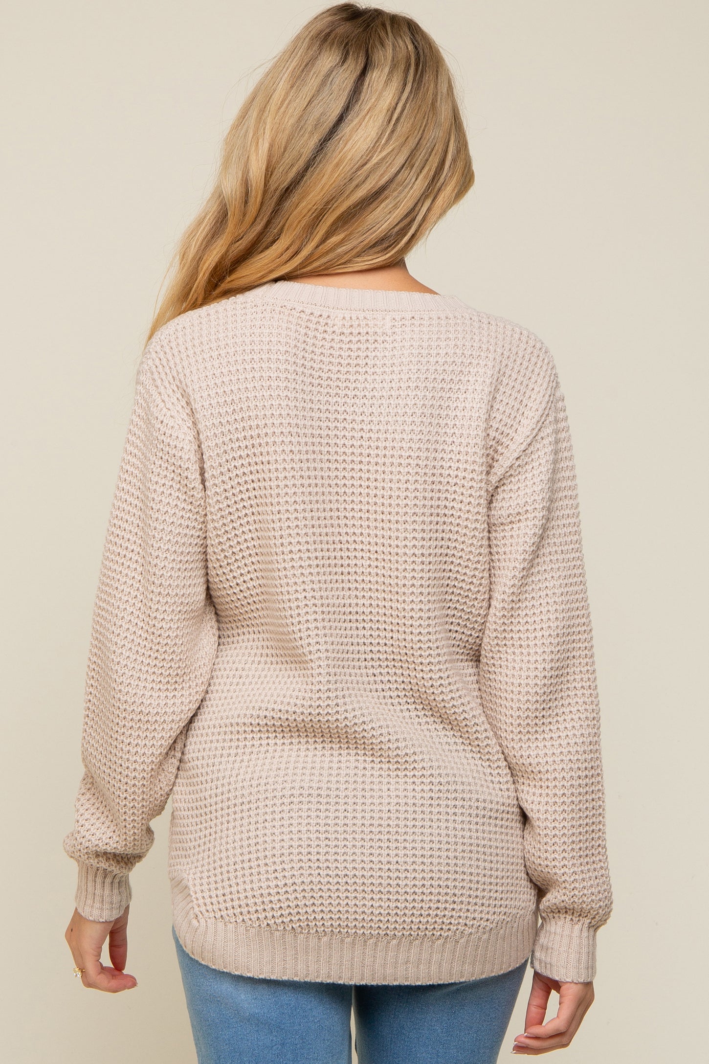 woman wearing a soft beige maternity sweater with a textured knit and long sleeves, view from the back