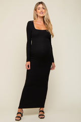 woman wearing a black ribbed long sleeve maternity dress with a square neckline and a visible baby bump