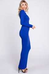 woman wearing a long sleeve royal blue fitted maxi dress and high heels standing in profile