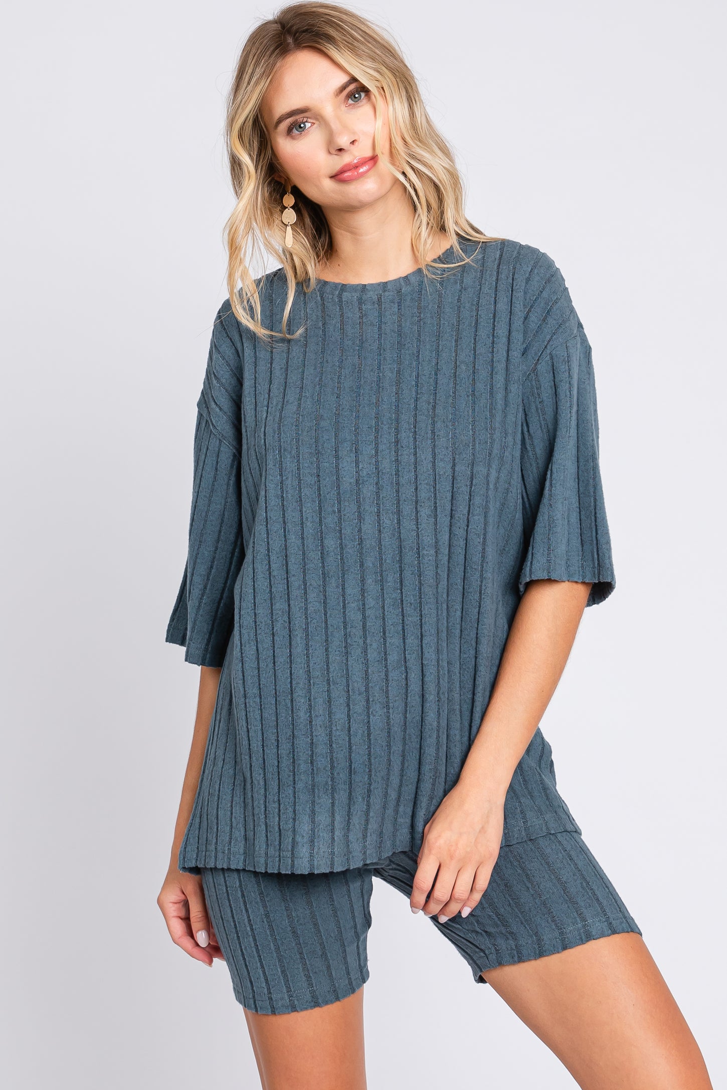 woman wearing a teal ribbed knit oversized top and matching shorts, styled casually with earrings