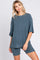 woman wearing a teal ribbed knit oversized top and matching shorts, styled casually with earrings