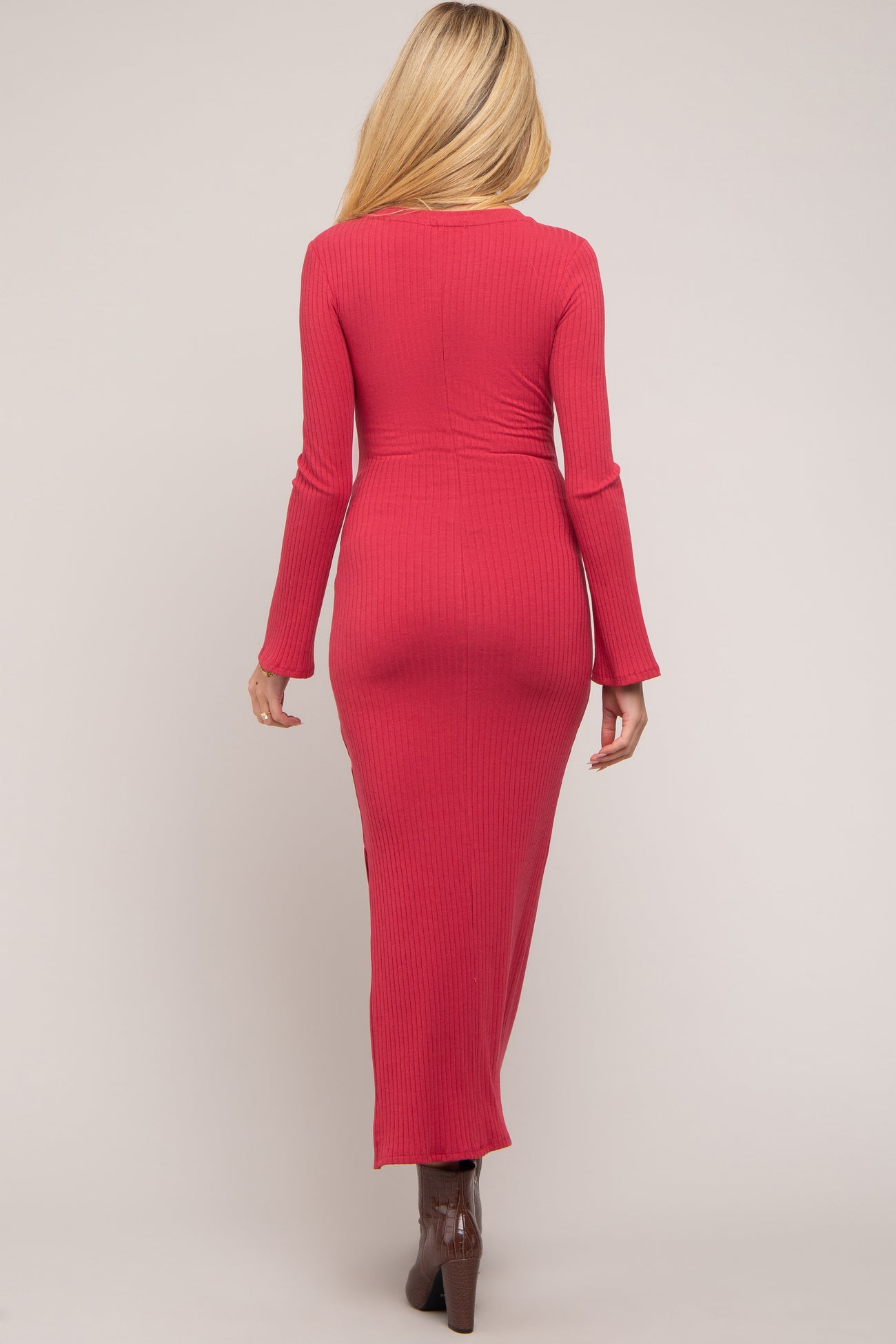 woman wearing a fitted raspberry long sleeve maternity dress with a round neck and a floor-length silhouette