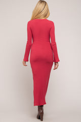 woman wearing a fitted raspberry long sleeve maternity dress with a round neck and a floor-length silhouette