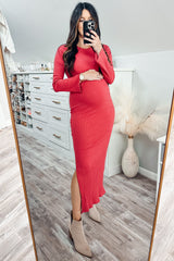 woman wearing a red ribbed maternity dress with a side slit and holding her baby bump