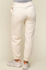 woman wearing cream maternity sweatpants with elastic cuffs and pockets, showing the back view