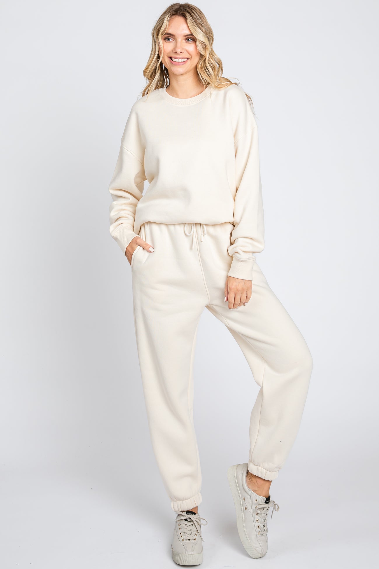 woman wearing a cream oversized sweatshirt and matching joggers, styled with a relaxed fit and side pockets