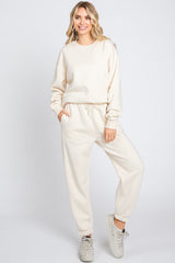 woman wearing a cream oversized sweatshirt and matching joggers, styled with a relaxed fit and side pockets