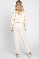 woman wearing a cream oversized sweatshirt and matching jogger pants, viewed from the back