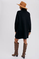 woman wearing a black oversized turtleneck dress with brown knee-high boots and a tan wide-brim hat