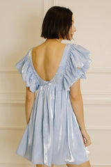 woman wearing a light blue backless dress with ruffled sleeves, showing a flowy silhouette from behind