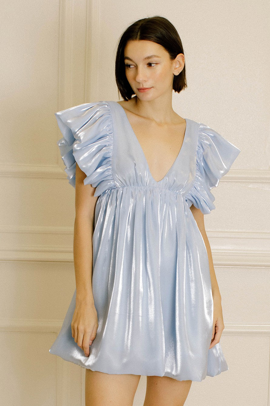 woman wearing a shiny light blue mini dress with dramatic ruffled sleeves and a deep v-neckline